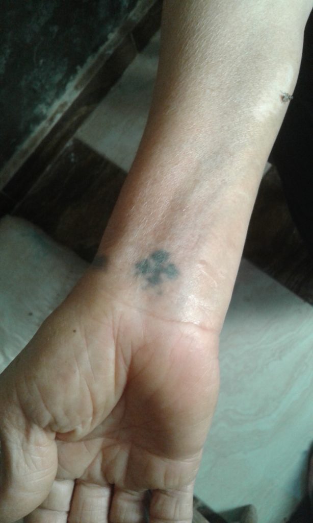 A photo of an Egyptian Coptic's wrist. They have a tattoo of a small cross on their wrist. 