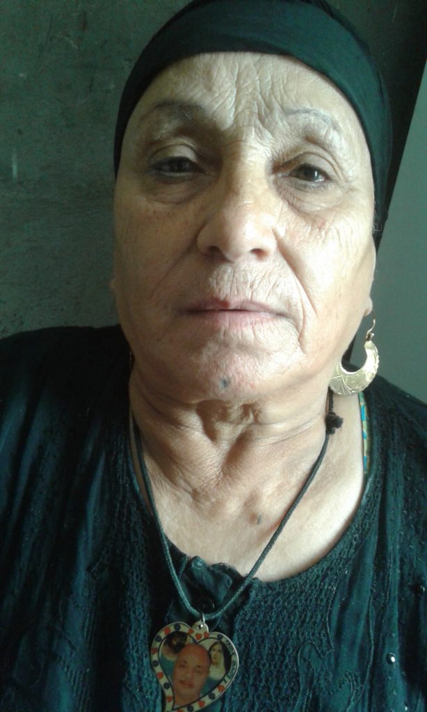 A photo of an Egyptian Copt. They are wearing a necklace with images of people, and a black top. 